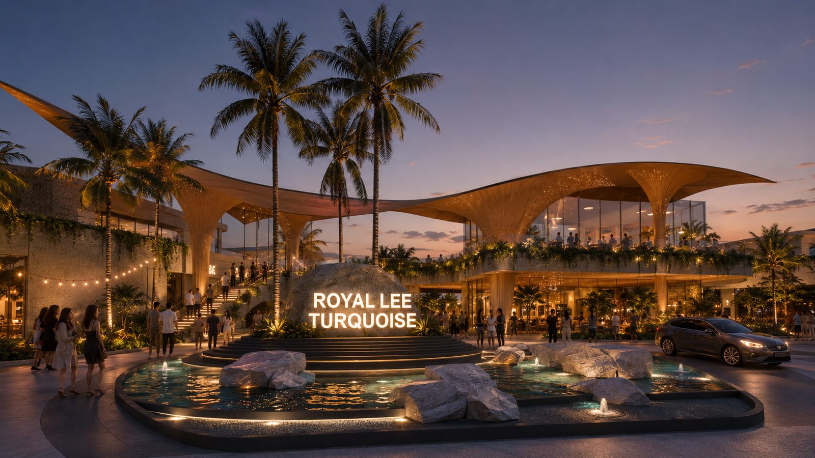 Royal Lee Turquoise Community Mall entrance plaza at dusk, with the illuminated project name on a rock water feature below the curved bamboo-style canopy roofs